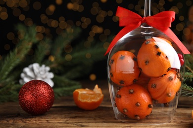 Photo of Christmas composition with tangerine pomander balls in wineglass on wooden table. Space for text