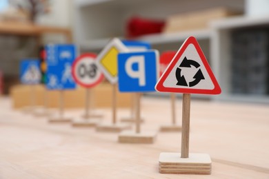 Photo of Different miniature road signs on wooden table, space for text. Montessori toy