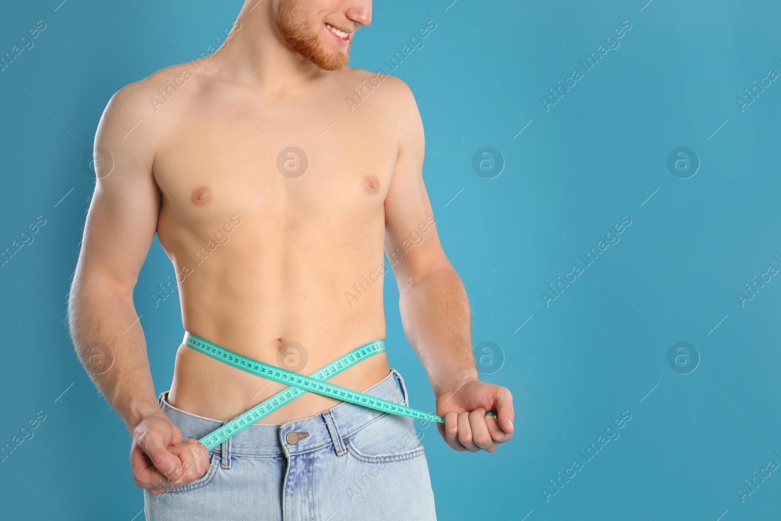 Photo of Man with slim body measuring his waist on color background, closeup. Space for text