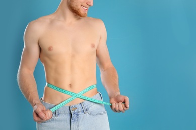 Photo of Man with slim body measuring his waist on color background, closeup. Space for text