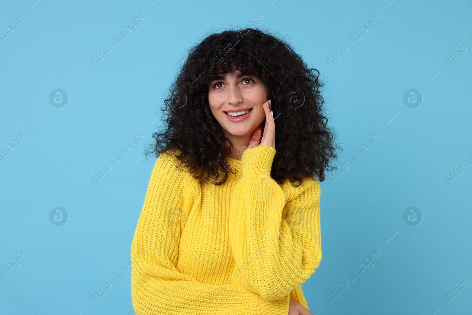 Photo of Happy young woman in stylish yellow sweater on light blue background