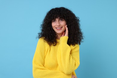 Happy young woman in stylish yellow sweater on light blue background