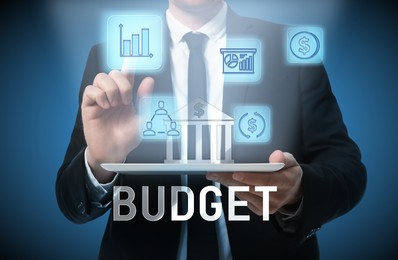 Image of Budget management. Businessman using tablet against blue background, closeup. Financial icons over device