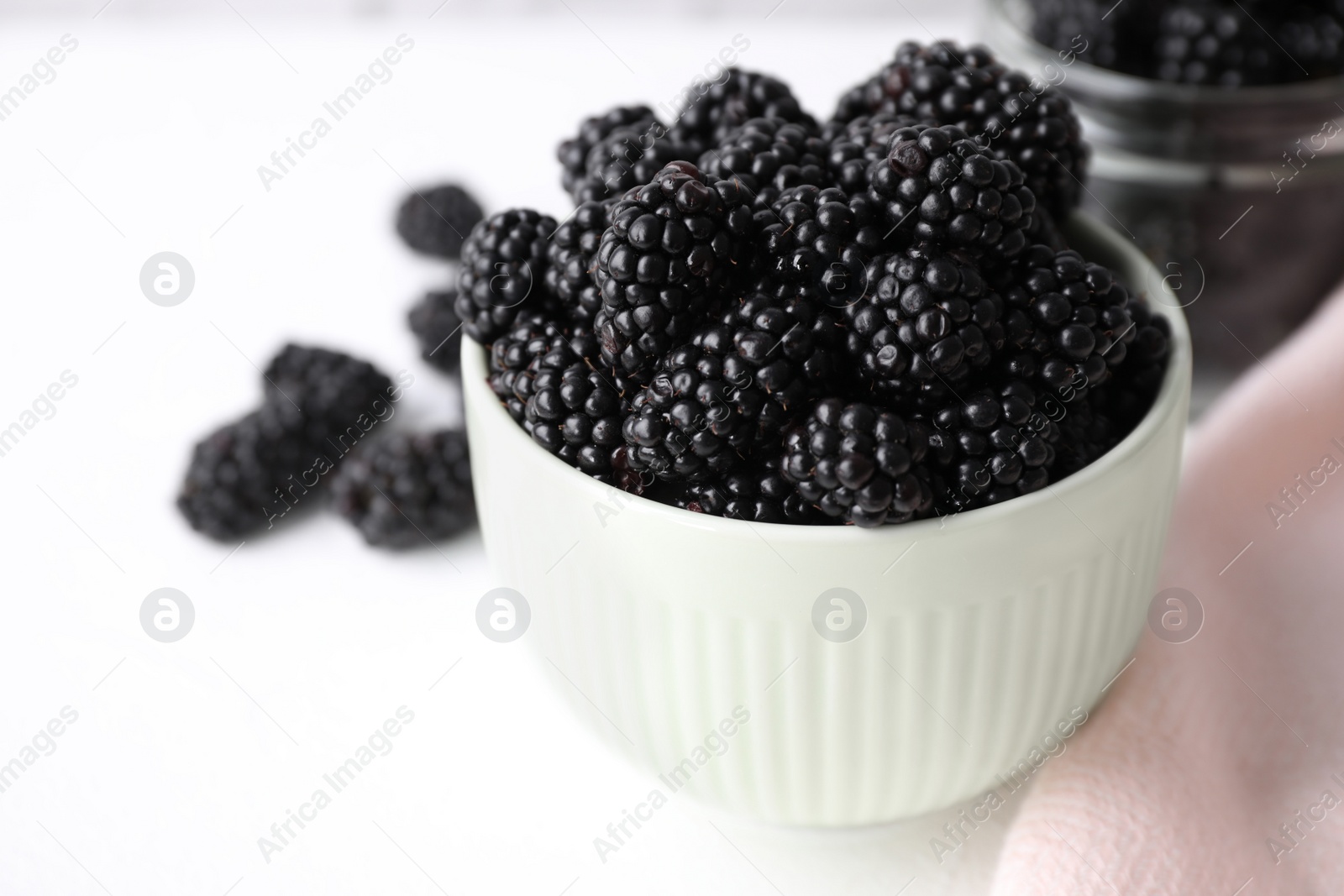 Photo of Delicious fresh ripe blackberries in bowl on white table, closeup