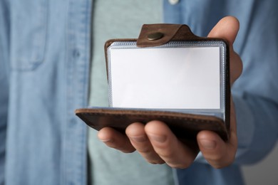 Photo of Man holding leather business card holder with blank card, closeup