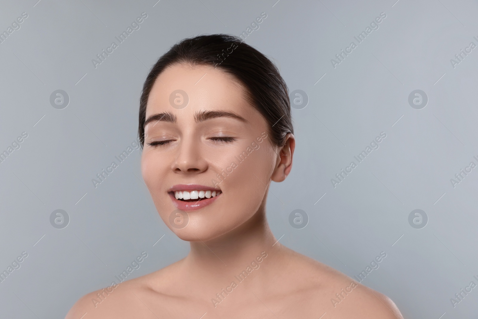 Photo of Portrait of attractive young woman with smooth skin on grey background