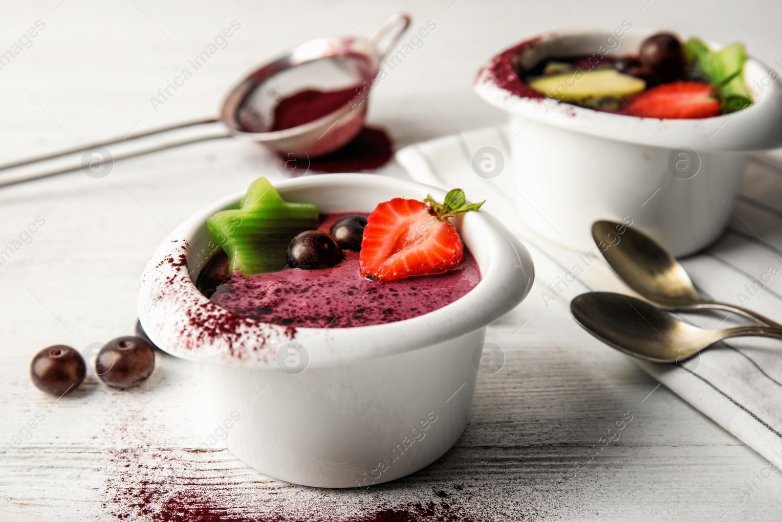 Photo of Bowls with tasty acai smoothie on light table