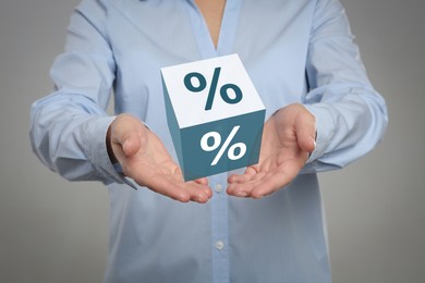 Image of Woman showing virtual cube with percent sign on light grey background, closeup. Discount concept