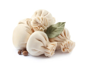 Photo of Pile of raw dumplings with bay leaf and pepper on white background