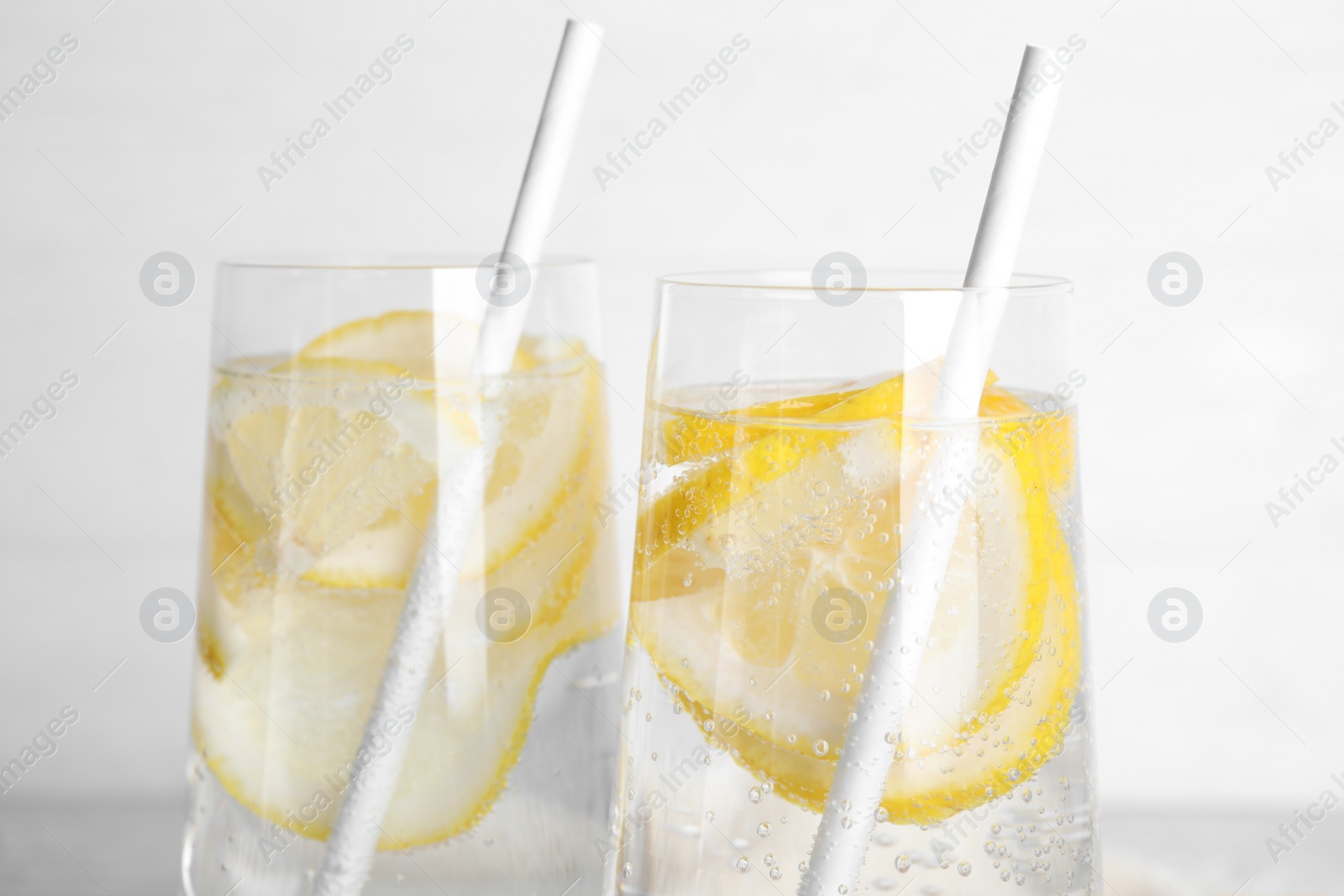 Photo of Soda water with lemon slices on light background, closeup