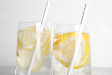 Photo of Soda water with lemon slices on light background, closeup