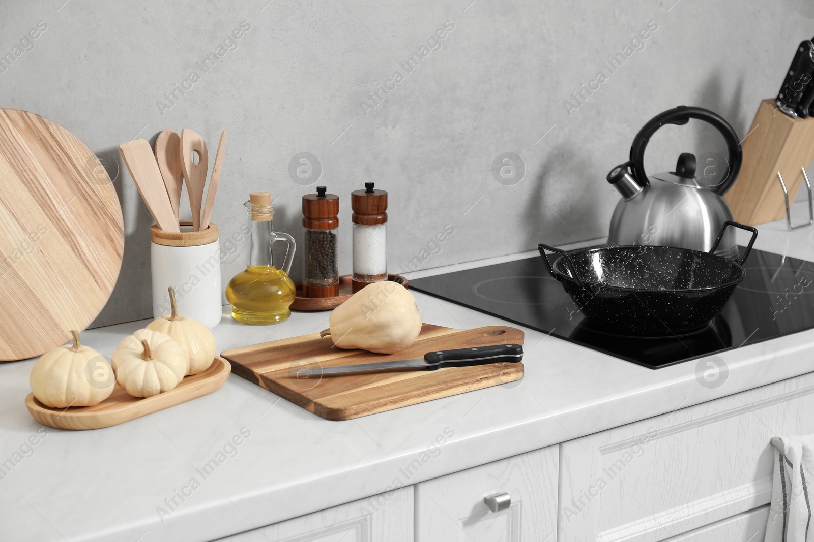 Photo of Wooden cutting boards, other cooking utensils and pumpkins on white countertop in kitchen