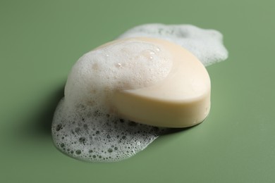 Photo of Soap and fluffy foam on green background