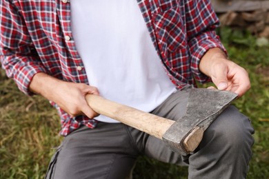 Photo of Man holding sharp ax with wooden handle outdoors, closeup