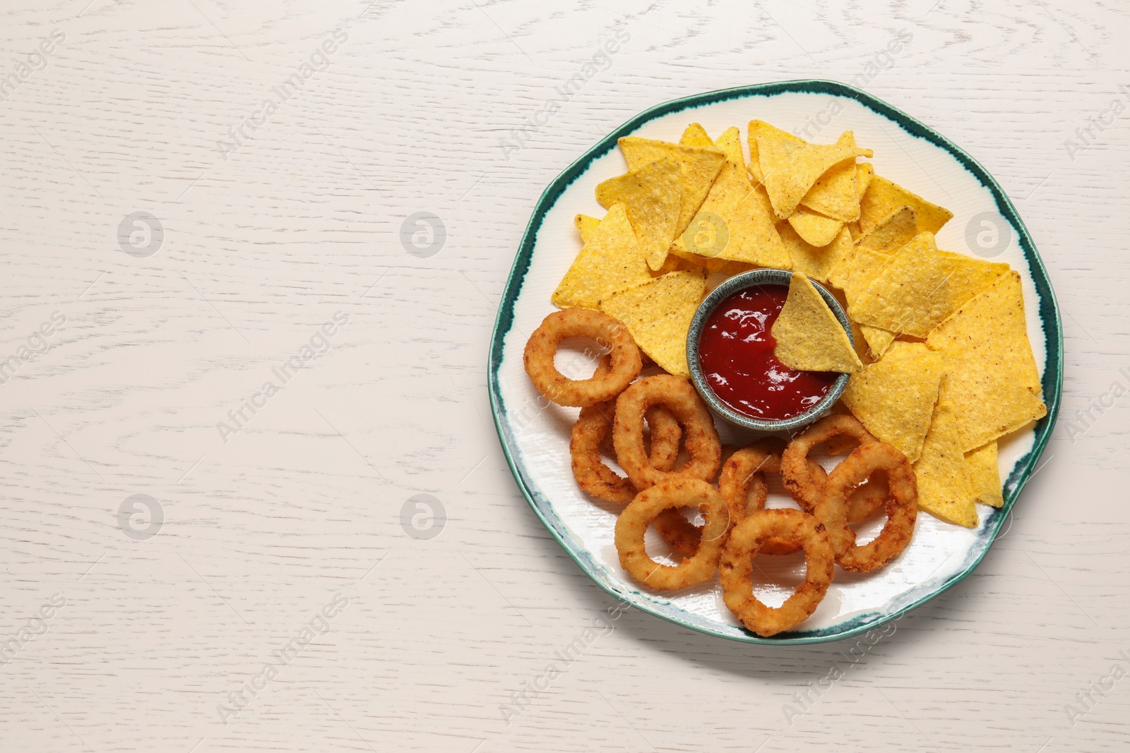 Photo of Tasty tortilla and fried onion rings with ketchup on white wooden table, top view. Space for text