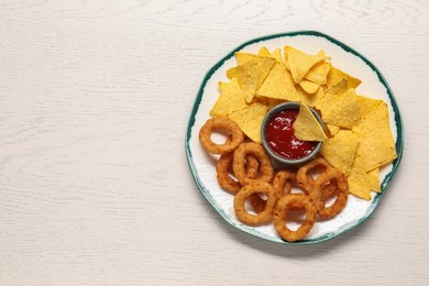 Tasty tortilla and fried onion rings with ketchup on white wooden table, top view. Space for text