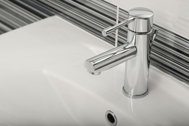 Clean white sink with shiny water tap in bathroom