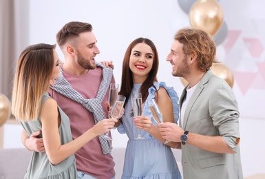 Happy friends with champagne in glasses at home