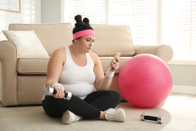 Photo of Lazy overweight woman using smartphone instead of morning training