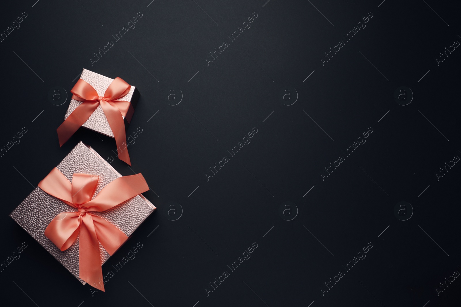 Photo of Gift boxes with satin bows on black background, flat lay. Space for text