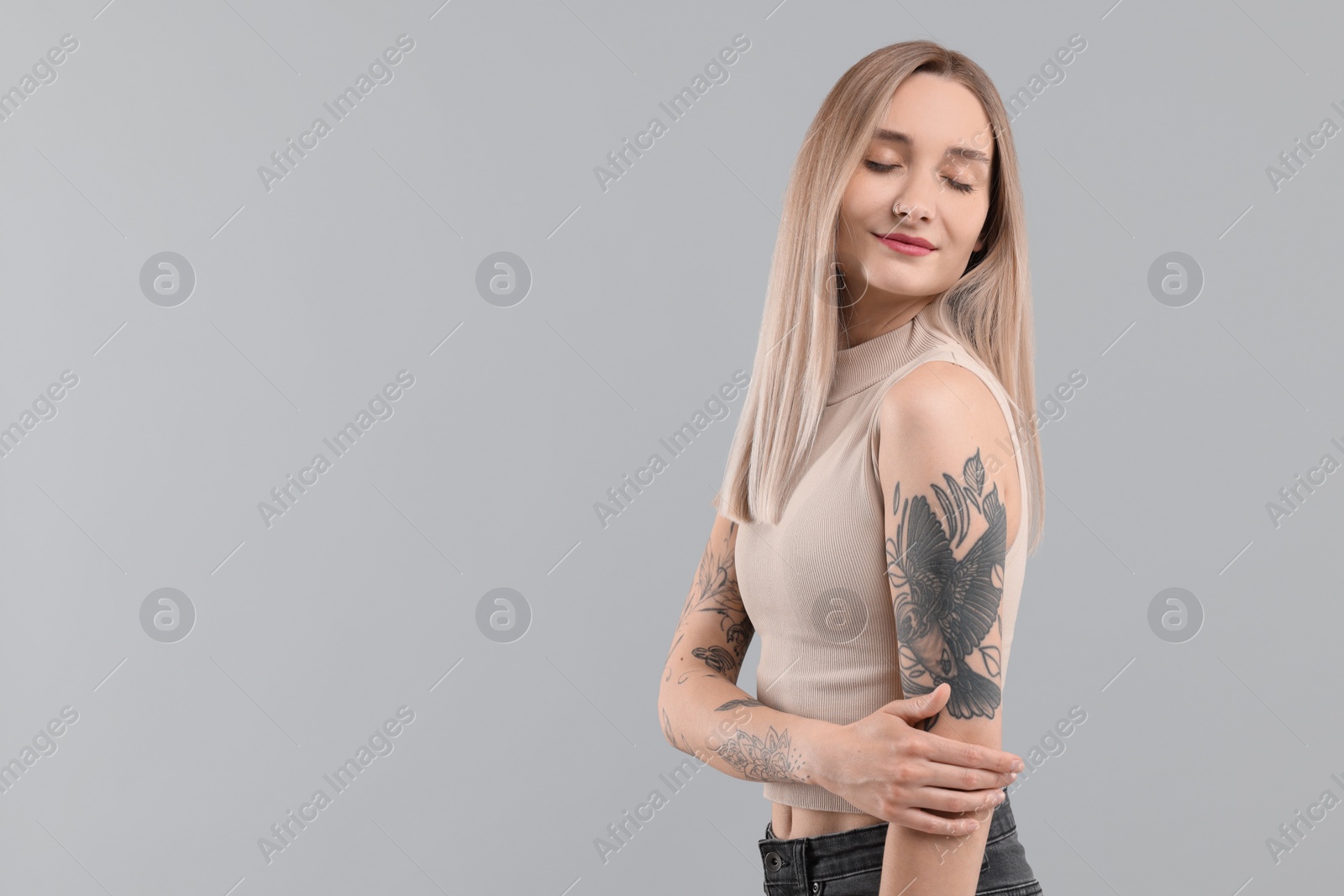 Photo of Portrait of beautiful tattooed woman on gray background, space for text