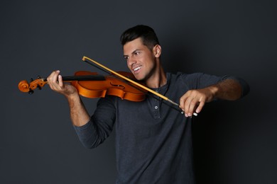 Happy man playing violin on black background