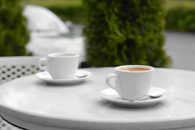 Photo of Ceramic cups of aromatic coffee with foam on table in morning