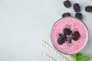 Photo of Flat lay composition with glass of delicious blackberry smoothie on light table. Space for text