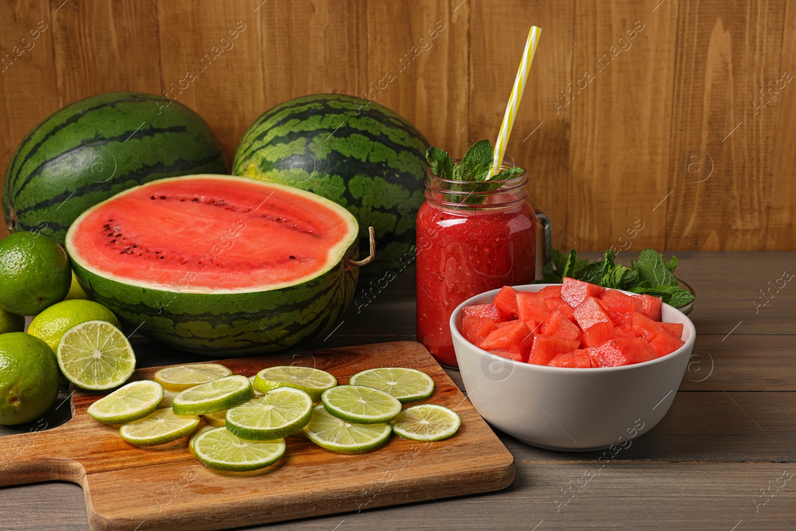 Photo of Tasty watermelon drink with lime and fresh ingredients on wooden table