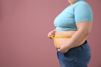 Photo of Overweight woman with measuring tape on color background