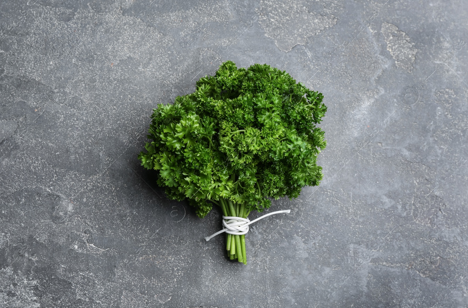 Photo of Bunch of fresh curly parsley on grey table, top view