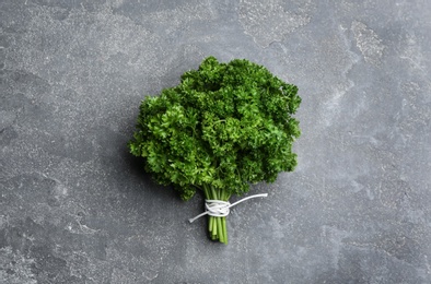 Bunch of fresh curly parsley on grey table, top view