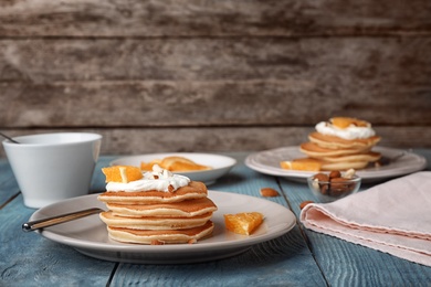 Tasty pancakes with orange on table