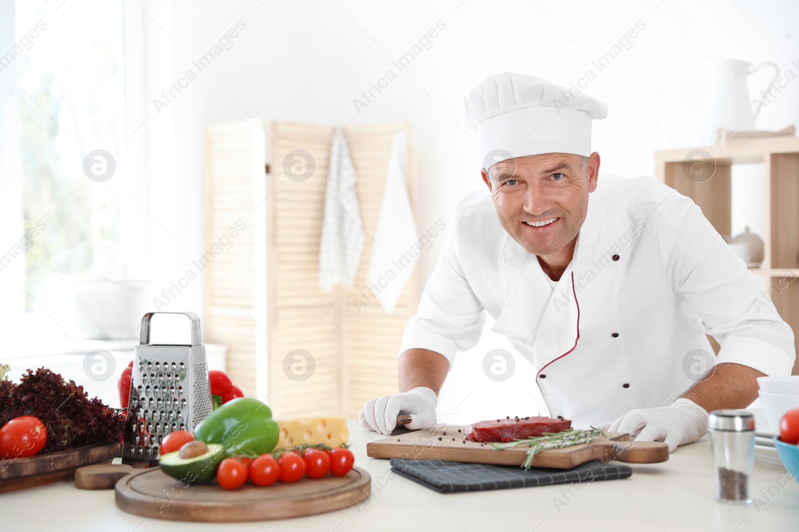 Photo of Professional chef cooking meat on table in kitchen