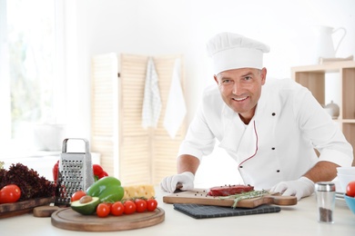 Photo of Professional chef cooking meat on table in kitchen