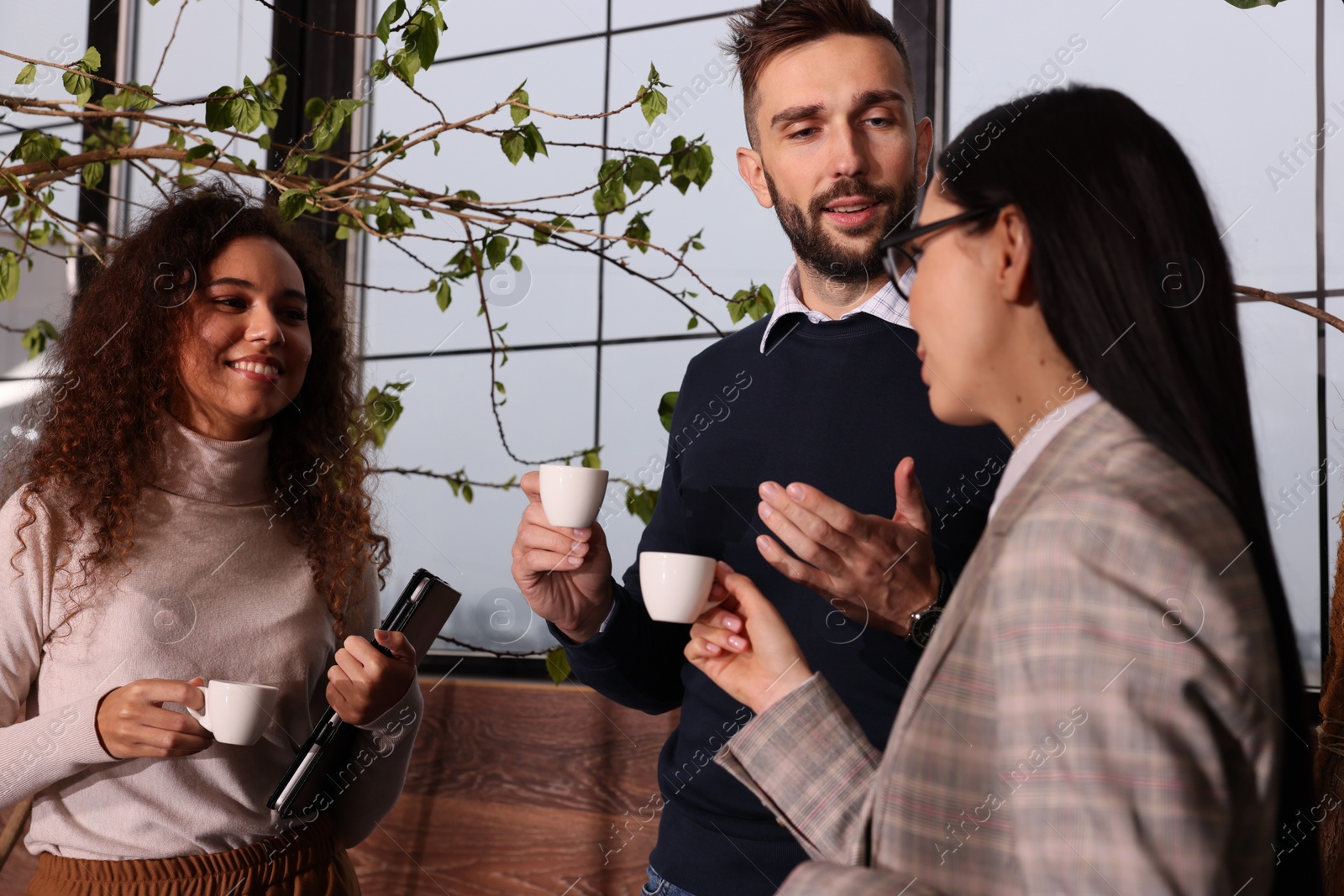 Photo of Group of coworkers talking during coffee break in office