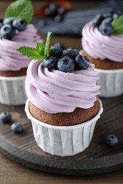 Photo of Sweet cupcake with fresh blueberries on wooden board, closeup