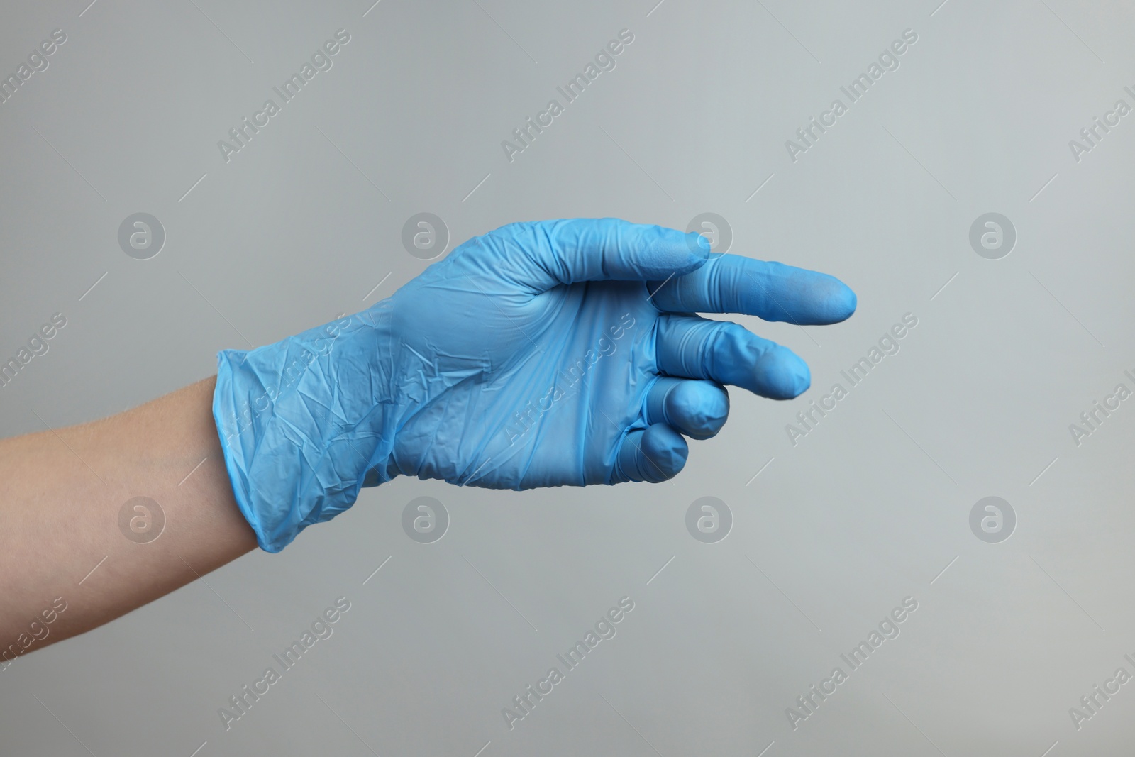 Photo of Doctor wearing light blue medical glove on grey background, closeup