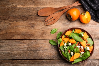 Photo of Delicious persimmon salad served on wooden table, flat lay. Space for text