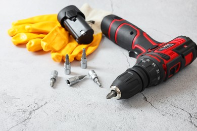 Photo of Electric screwdriver, drill bits, battery and gloves on light table