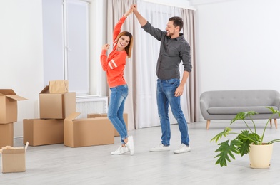 Photo of Happy couple dancing near moving boxes in their new house