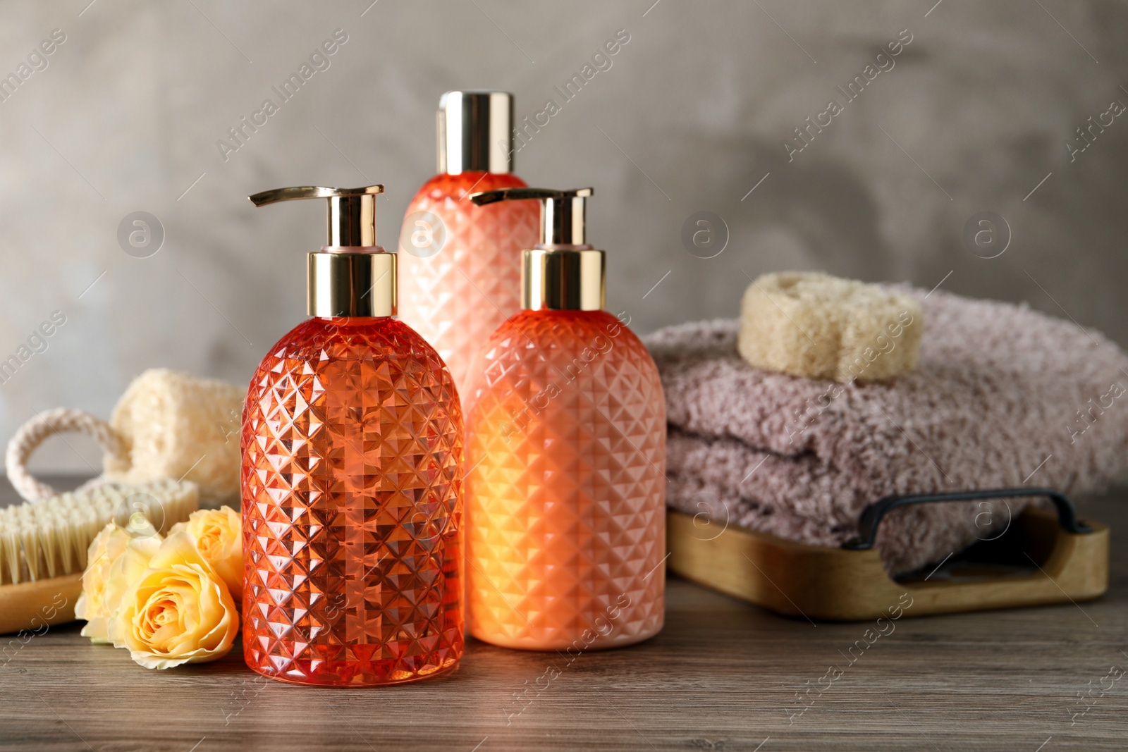 Photo of Stylish dispensers with liquid soap and other bathroom amenities on wooden table, space for text