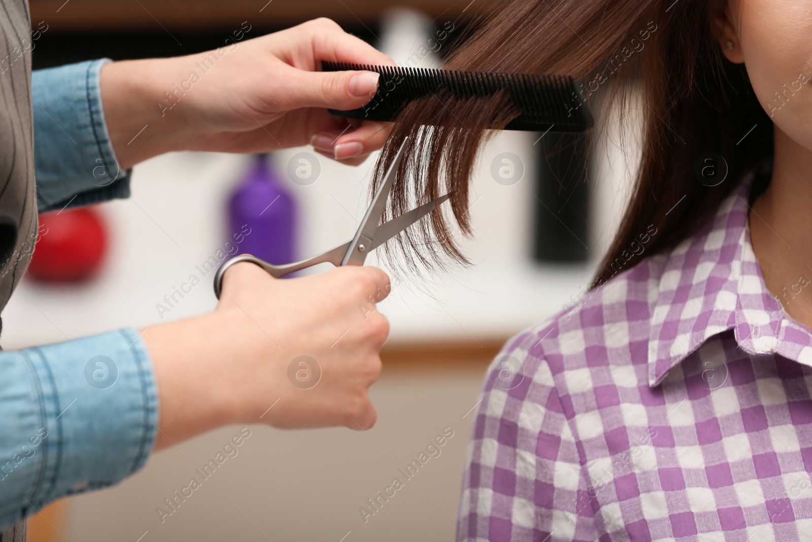 Photo of Barber making stylish haircut with professional scissors in beauty salon, closeup