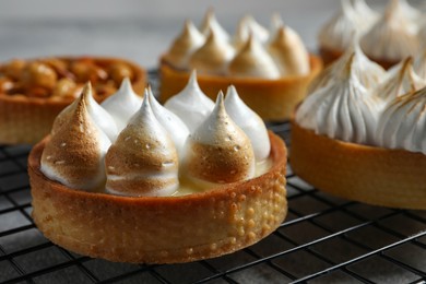Photo of Many different tartlets on cooling tray, closeup. Tasty dessert