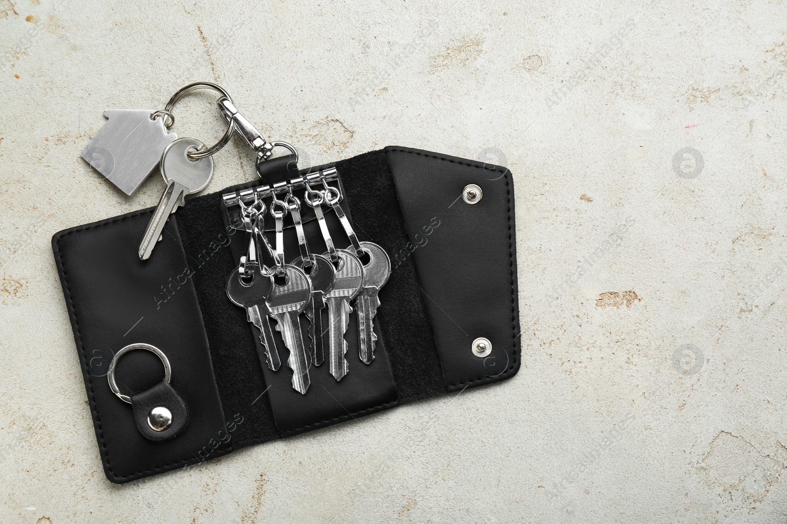 Photo of Stylish leather holder with keys on light grey table, top view. Space for text