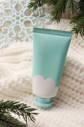 Photo of Winter skin care. Hand cream and fir branches on white knitted cloth