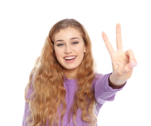 Photo of Happy young woman showing victory gesture on white background