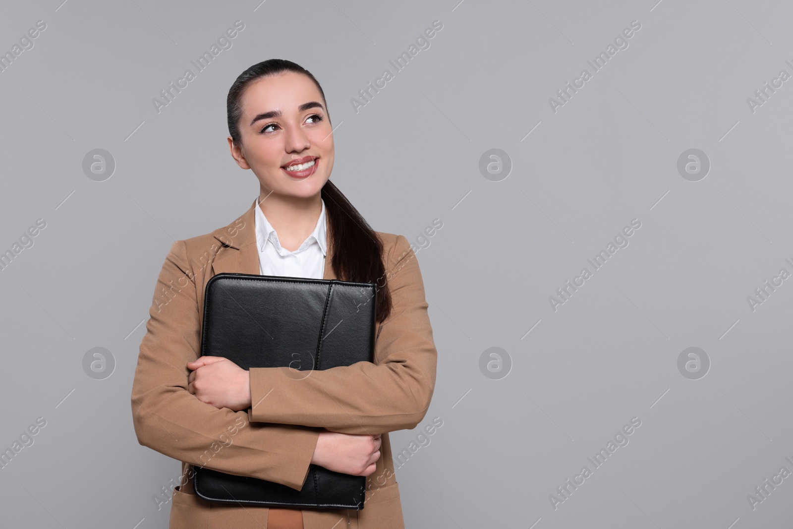 Photo of Happy real estate agent with leather portfolio on grey background. Space for text