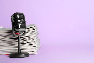 Photo of Newspapers and vintage microphone on light violet background, space for text. Journalist's work