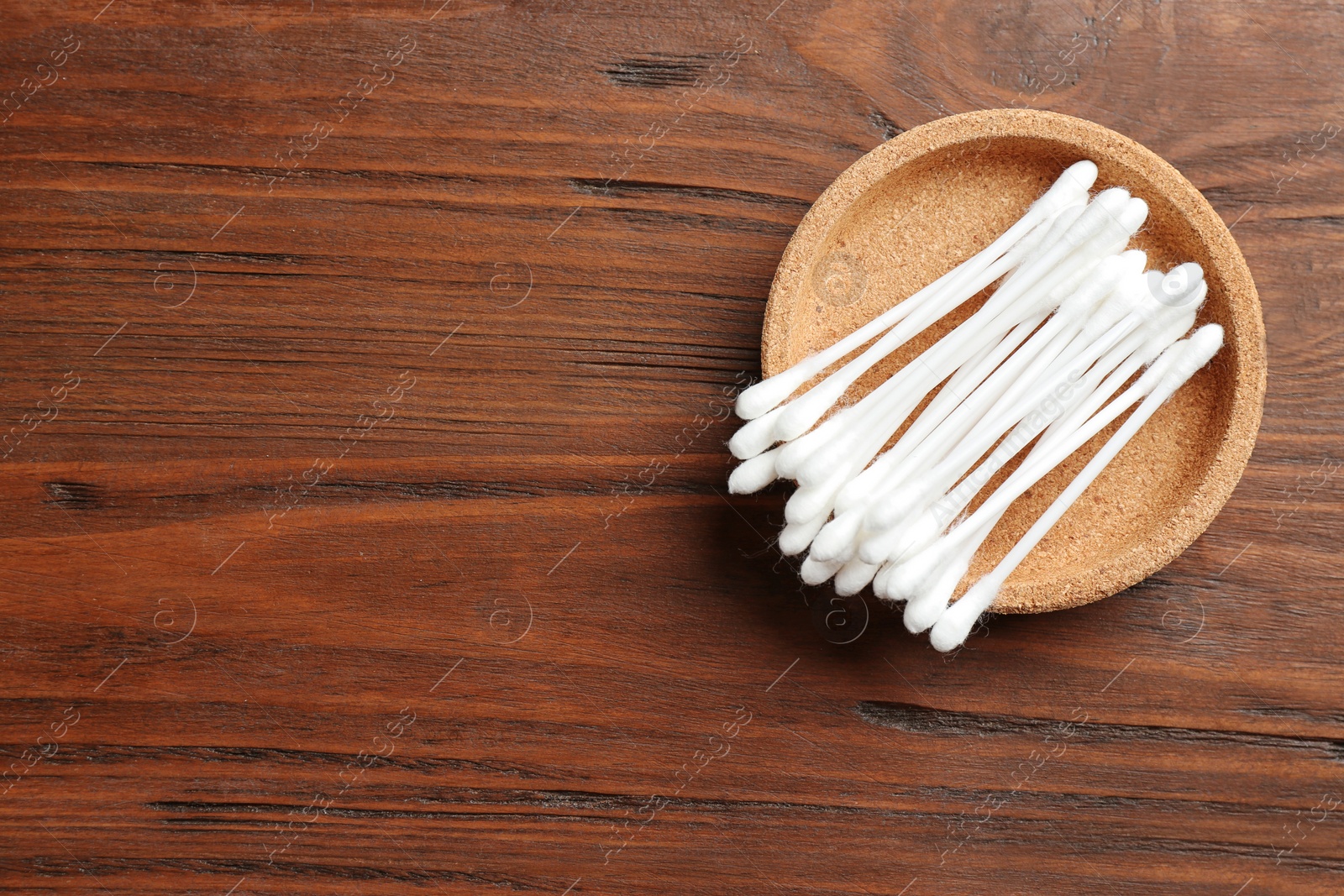 Photo of Plate with cotton swabs on wooden background, top view. Space for text